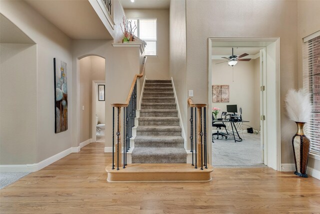 15606 Fox Meadow Ln, Frisco, TX 75035 - stairs featuring arched walkways, ceiling fan, wood finished floors, baseboards, and a high ceiling
