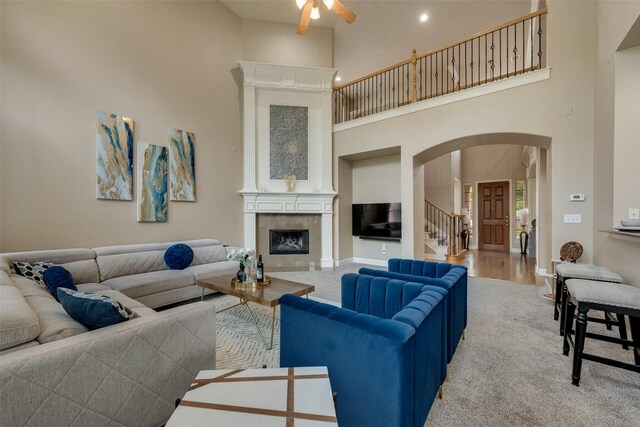 15606 Fox Meadow Ln, Frisco, TX 75035 - carpeted living room with arched walkways, a high ceiling, ceiling fan, a tiled fireplace, and baseboards