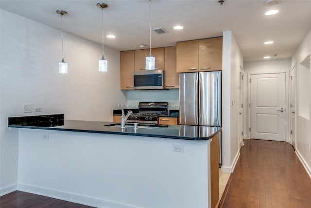 1200 Main St Unit 707, Dallas, TX 75202 - kitchen with stainless steel appliances, a peninsula, dark countertops, wood finished floors, and a sink