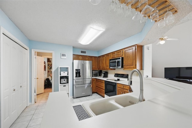 2708 Van Gogh Pl, Dallas, TX 75287 - kitchen with stainless steel appliances, brown cabinets, light tile patterned floors, light countertops, and a textured ceiling