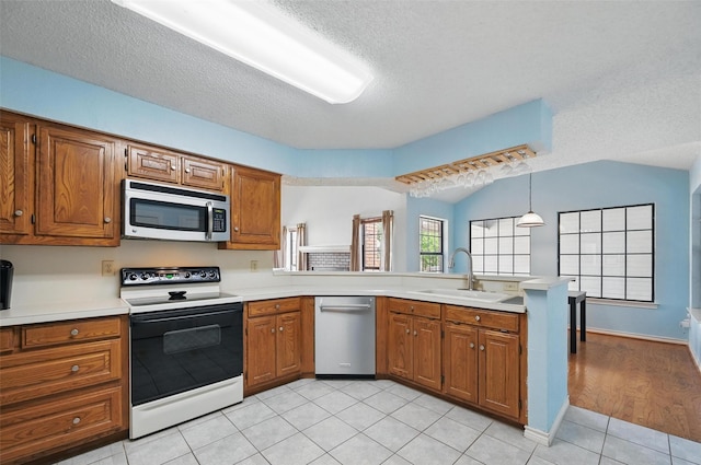 2708 Van Gogh Pl, Dallas, TX 75287 - kitchen featuring appliances with stainless steel finishes, a sink, brown cabinets, a textured ceiling, and vaulted ceiling