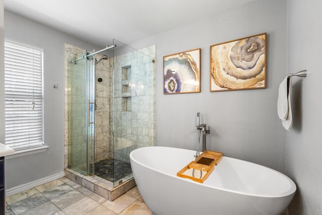 full bath featuring a stall shower, a freestanding tub, baseboards, and marble finish flooring