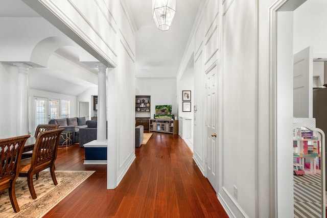 hall with ornate columns and dark wood-style flooring