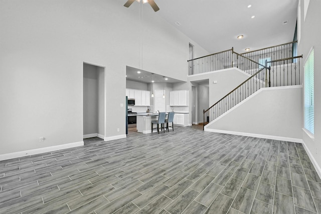 1017 Lade Ct, Celina, TX 75009 - unfurnished living room with baseboards, ceiling fan, a towering ceiling, wood finished floors, and stairway