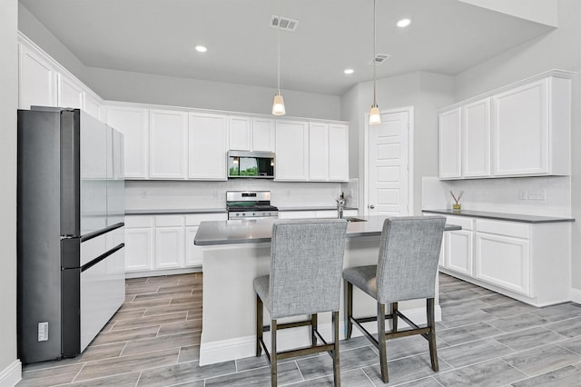 1017 Lade Ct, Celina, TX 75009 - kitchen featuring stainless steel appliances, white cabinets, decorative backsplash, recessed lighting, and wood finish floors