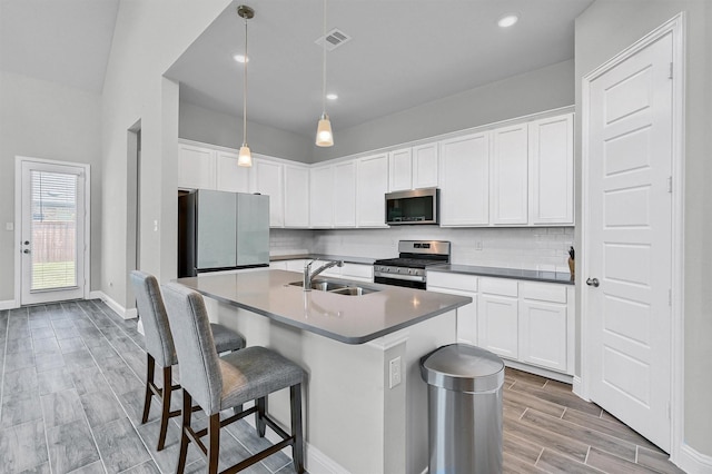 1017 Lade Ct, Celina, TX 75009 - kitchen featuring stainless steel appliances, a sink, light wood-style floors, decorative backsplash, and a center island with sink