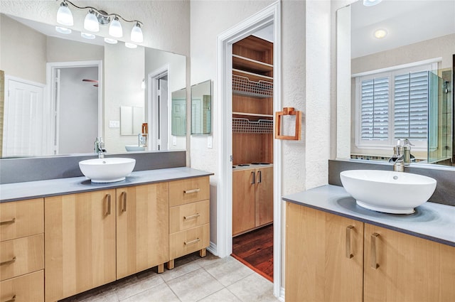 bathroom with two vanities, a textured wall, tile patterned flooring, and a closet
