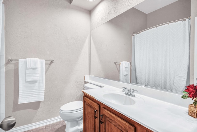 bathroom with a textured wall, toilet, vanity, baseboards, and curtained shower