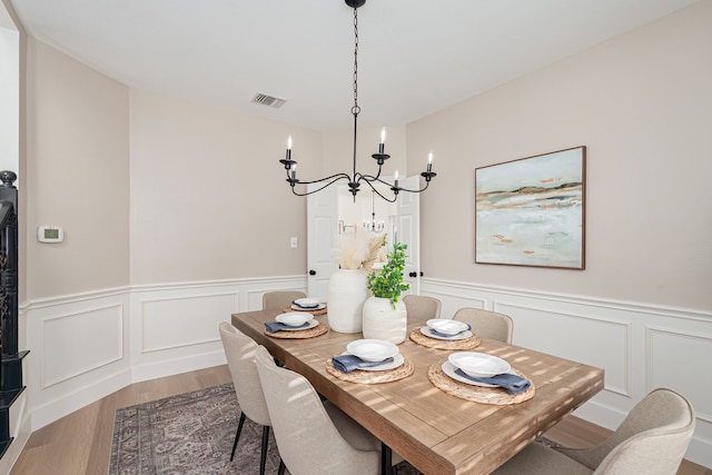 7901 Cross Plains Dr, Plano, TX 75025 - dining room featuring wood finished floors, a chandelier, wainscoting, and a decorative wall