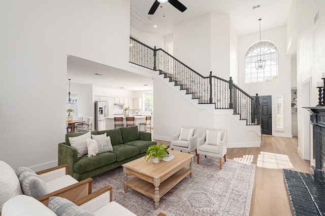 7901 Cross Plains Dr, Plano, TX 75025 - living room featuring a towering ceiling, a chandelier, a ceiling fan, light wood finished floors, and stairway