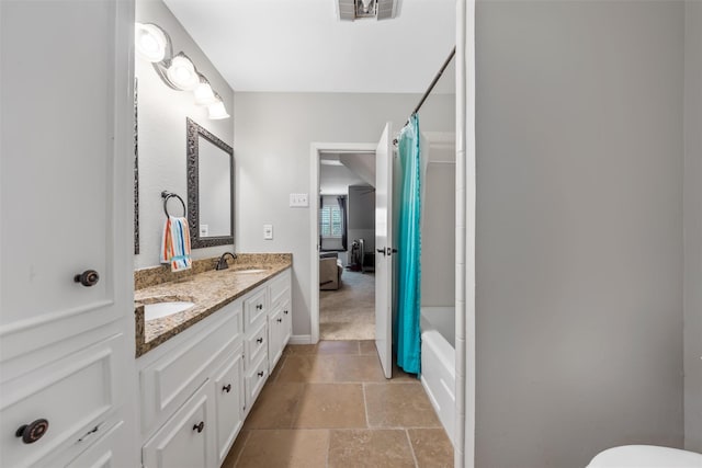 7125 Fish Pond Rd, Waco, TX 76710 - bathroom with stone tile flooring, double vanity, shower / bath combo with shower curtain, toilet, and baseboards