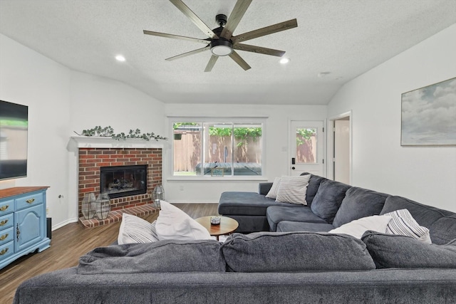 1010 Greenbriar Ln, Mckinney, TX 75069 - living room featuring vaulted ceiling, a textured ceiling, a ceiling fan, dark wood-style floors, and a fireplace