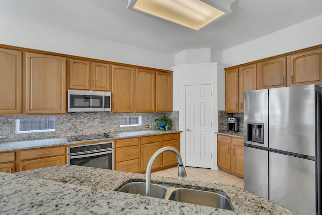 kitchen featuring appliances with stainless steel finishes, a sink, and light stone counters
