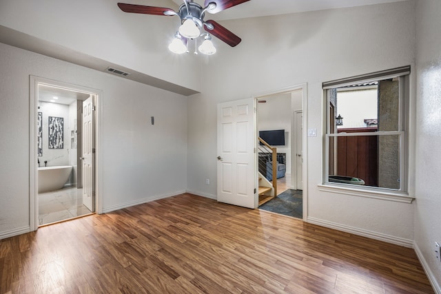 4242 N Capistrano Dr Unit 174, Dallas, TX 75287 - unfurnished bedroom with wood finished floors, baseboards, connected bathroom, a ceiling fan, and a towering ceiling