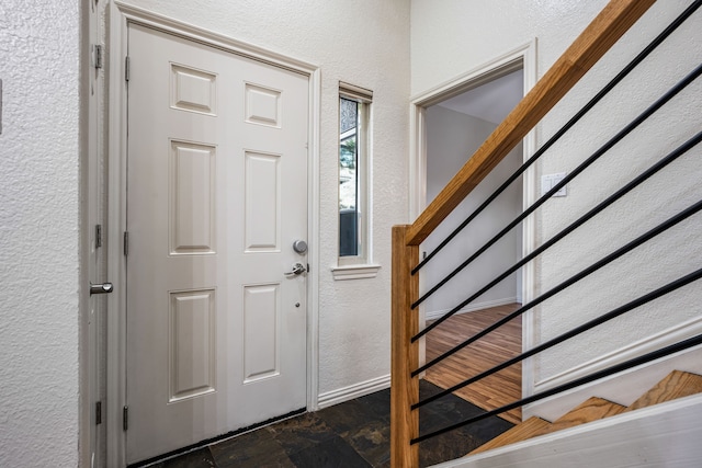 4242 N Capistrano Dr Unit 174, Dallas, TX 75287 - foyer entrance featuring a textured wall, stairway, dark stone finish flooring, and baseboards