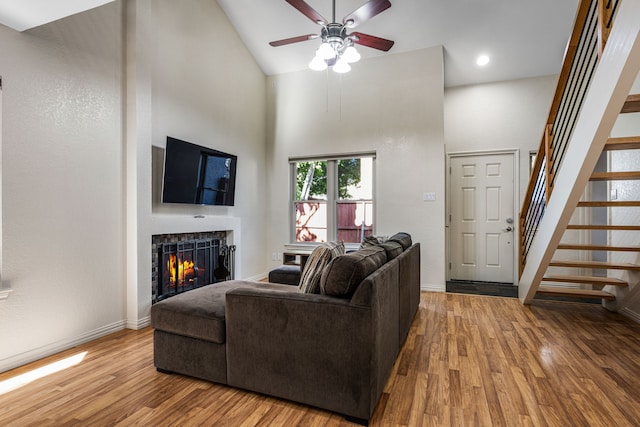 4242 N Capistrano Dr Unit 174, Dallas, TX 75287 - living room with a warm lit fireplace, a ceiling fan, wood finished floors, stairway, and high vaulted ceiling