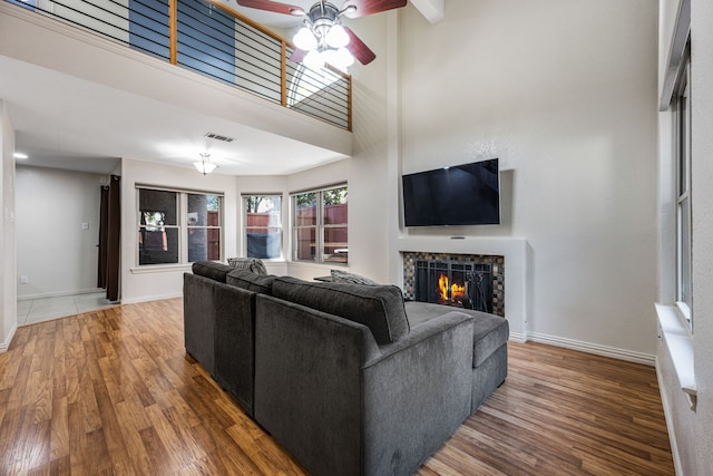 4242 N Capistrano Dr Unit 174, Dallas, TX 75287 - living area featuring ceiling fan, wood finished floors, a lit fireplace, baseboards, and a towering ceiling