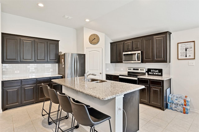 9220 Nevis Dr, Fort Worth, TX 76123 - kitchen featuring appliances with stainless steel finishes, a sink, light tile patterned flooring, vaulted ceiling, and decorative backsplash