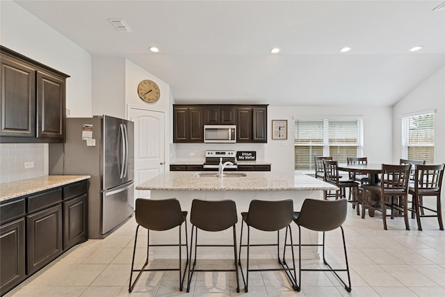 9220 Nevis Dr, Fort Worth, TX 76123 - kitchen featuring appliances with stainless steel finishes, a kitchen breakfast bar, backsplash, light tile patterned floors, and recessed lighting