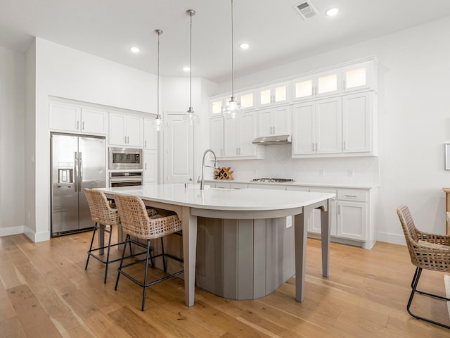 317 Legna Dr, Aledo, TX 76008 - kitchen with appliances with stainless steel finishes, backsplash, a breakfast bar area, white cabinetry, and light wood-type flooring