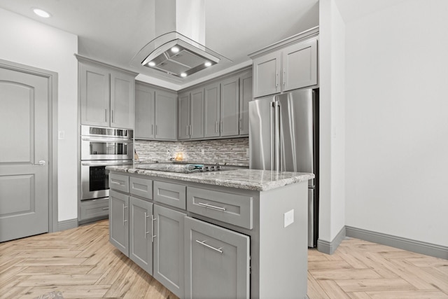 3304 Cobbler Ln, Joshua, TX 76058 - kitchen with gray cabinets, appliances with stainless steel finishes, wall chimney range hood, decorative backsplash, and a center island