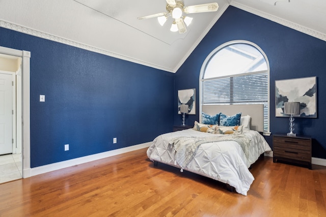 bedroom with lofted ceiling, wood finished floors, crown molding, ceiling fan, and baseboards