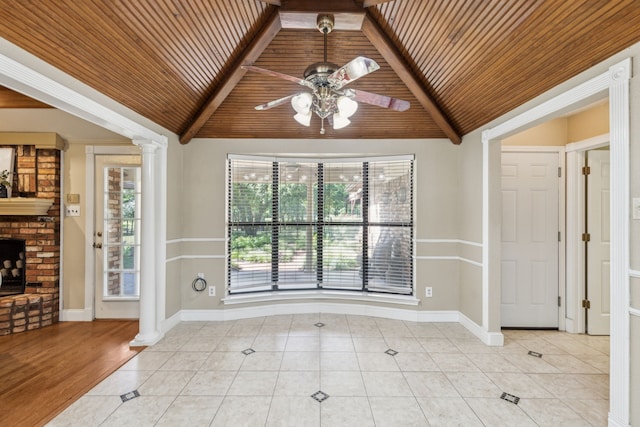 spare room with wooden ceiling, lofted ceiling, ceiling fan, light tile patterned floors, and a brick fireplace