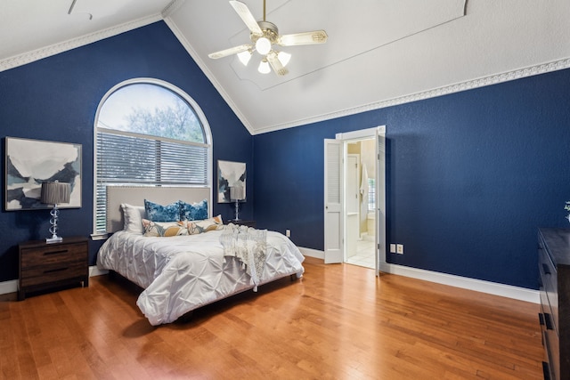 bedroom with wood finished floors, vaulted ceiling, a ceiling fan, connected bathroom, and baseboards