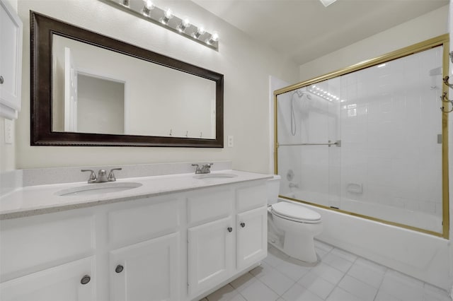 bathroom with tile patterned flooring, double vanity, toilet, and bath / shower combo with glass door