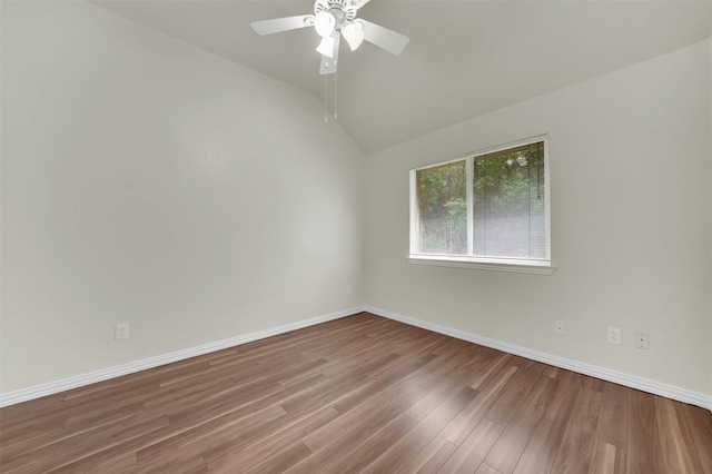 empty room with wood finished floors, a ceiling fan, lofted ceiling, and baseboards