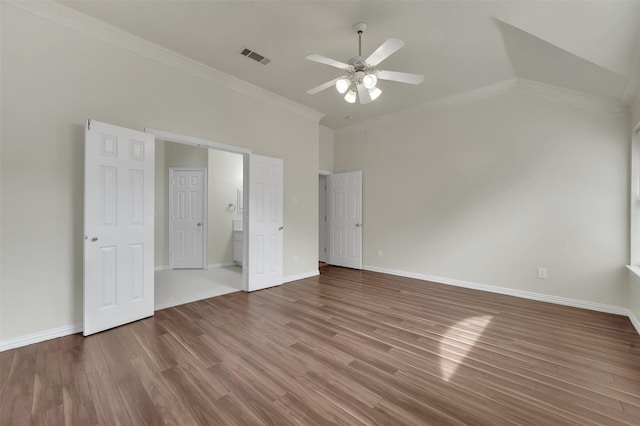 unfurnished bedroom featuring wood finished floors, crown molding, baseboards, a ceiling fan, and vaulted ceiling