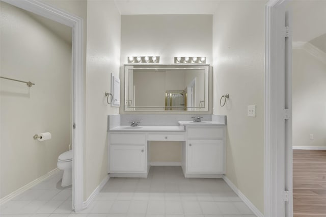 full bathroom featuring baseboards, double vanity, and toilet