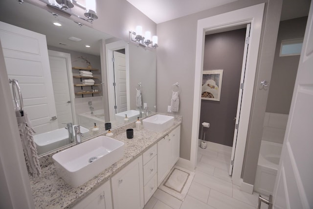 bathroom featuring double vanity, baseboards, a tub, and tile patterned flooring
