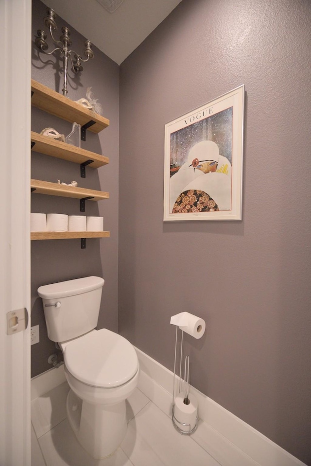 bathroom with toilet, marble finish flooring, and baseboards
