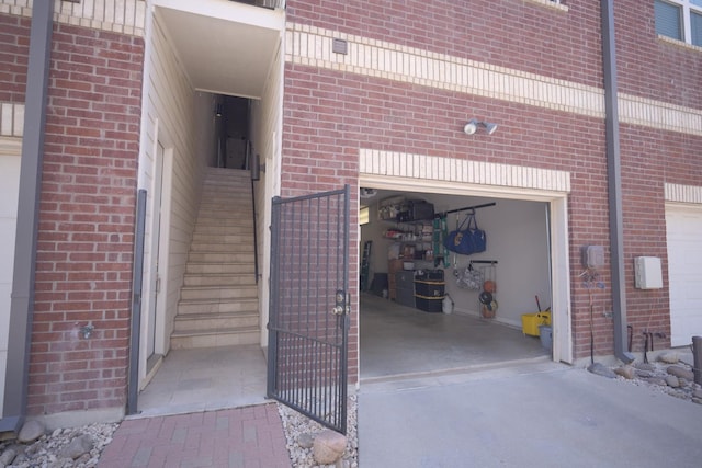 property entrance with brick siding, an attached garage, and concrete driveway