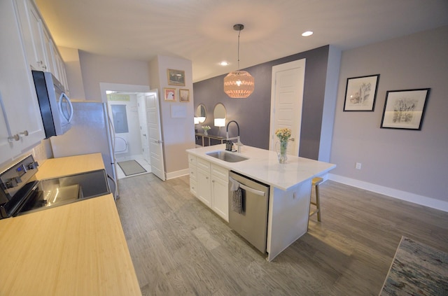 kitchen featuring stainless steel appliances, a sink, white cabinetry, a center island with sink, and dark wood finished floors