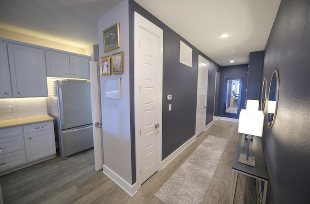 hallway featuring light wood-style flooring, baseboards, and recessed lighting