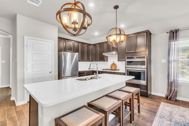 2125 Swanmore Way, Forney, TX 75126 - kitchen featuring stainless steel appliances, a chandelier, a sink, dark brown cabinets, and baseboards