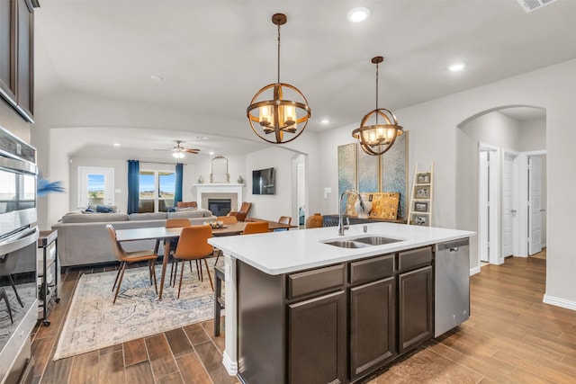2125 Swanmore Way, Forney, TX 75126 - kitchen featuring dishwasher, a glass covered fireplace, arched walkways, a sink, and dark wood-style flooring