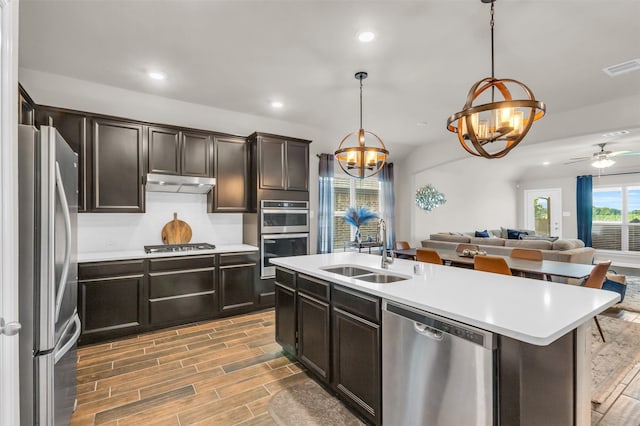 2125 Swanmore Way, Forney, TX 75126 - kitchen featuring appliances with stainless steel finishes, a sink, under cabinet range hood, a chandelier, and open floor plan
