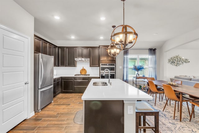 2125 Swanmore Way, Forney, TX 75126 - kitchen featuring appliances with stainless steel finishes, a sink, light wood-style flooring, dark brown cabinets, and a chandelier