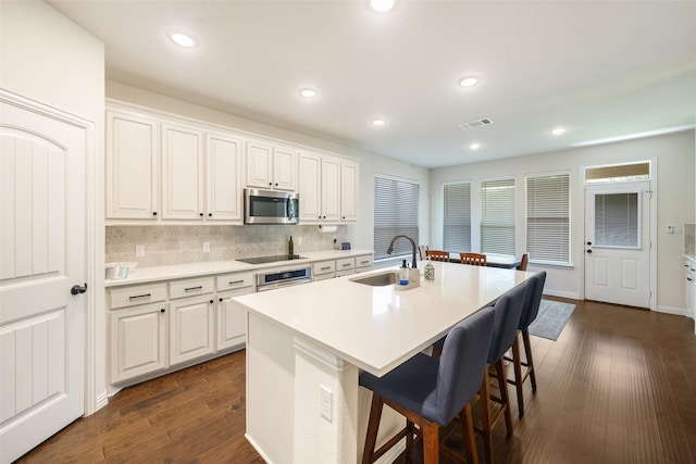 3129 Greymoore Dr, Anna, TX 75409 - kitchen featuring a sink, appliances with stainless steel finishes, a breakfast bar area, dark wood-style floors, and a kitchen island with sink