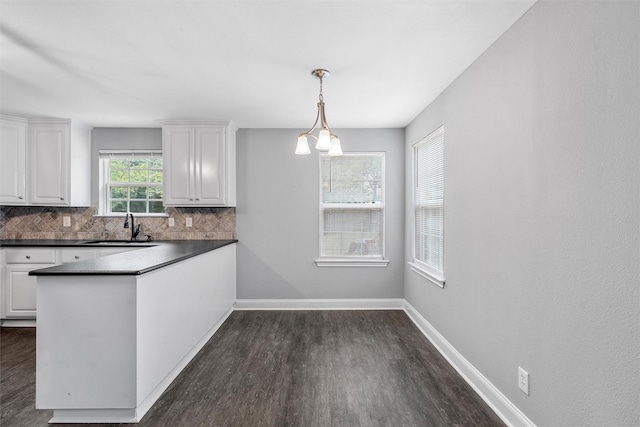 4016 Austin Ave, Waco, TX 76710 - kitchen with a sink, dark wood-style floors, white cabinetry, dark countertops, and tasteful backsplash