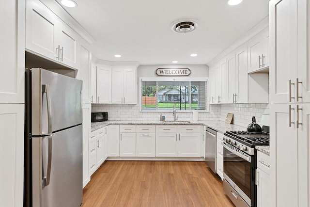 2409 Janice Ln, Fort Worth, TX 76112 - kitchen with appliances with stainless steel finishes, a sink, white cabinetry, light wood-style floors, and recessed lighting