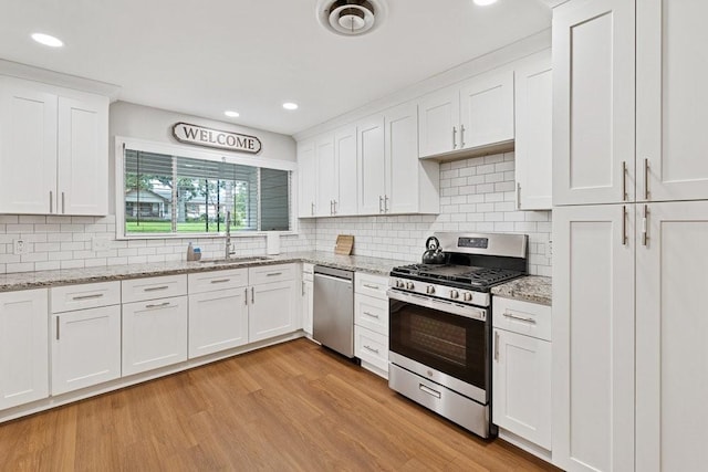2409 Janice Ln, Fort Worth, TX 76112 - kitchen with appliances with stainless steel finishes, a sink, white cabinets, light wood-style floors, and tasteful backsplash