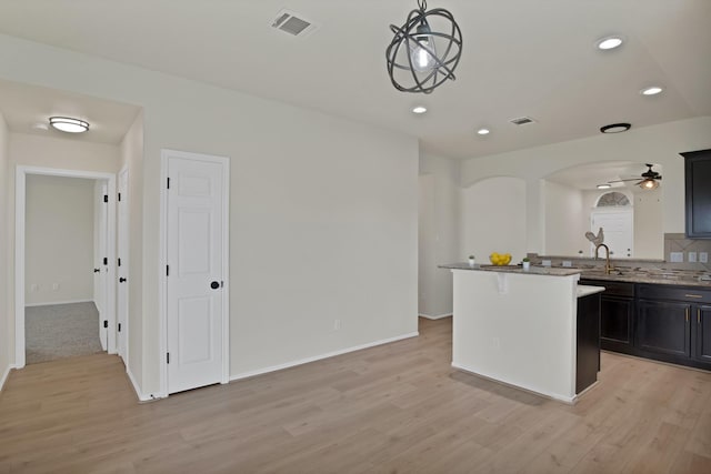 10152 Parker Springs Dr, Waco, TX 76708 - kitchen featuring light wood finished floors, arched walkways, recessed lighting, a ceiling fan, and light stone countertops