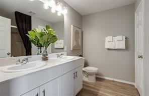 254 Lake Erie Dr, Princeton, TX 75407 - bathroom with baseboards, double vanity, toilet, and wood finished floors