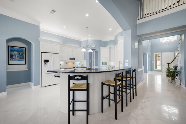 2410 Gail St, Royse City, TX 75189 - kitchen with white appliances, dark countertops, arched walkways, a breakfast bar, and ornamental molding