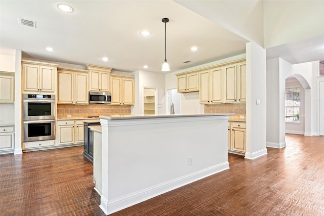 8604 Preston Wood Dr, Mckinney, TX 75072 - kitchen with cream cabinetry, stainless steel appliances, arched walkways, backsplash, and recessed lighting