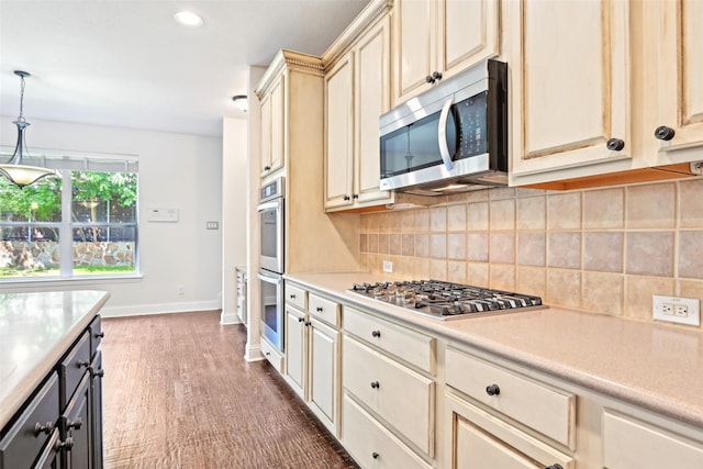8604 Preston Wood Dr, Mckinney, TX 75072 - kitchen featuring appliances with stainless steel finishes, light countertops, cream cabinetry, baseboards, and tasteful backsplash